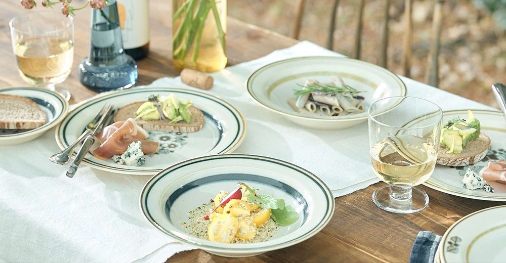 陶瓷深盤，盤面有葉紋圖案，盤緣有深藍色與金色的線條裝飾，盤中盛有食物，呈現復古溫潤的質感。