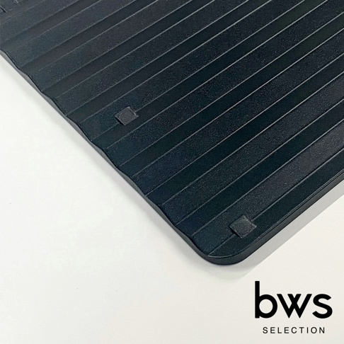 一張黑色食物快速冷卻盤的特寫，盤面帶有平行凹槽，四個角落下方有白色防滑墊。