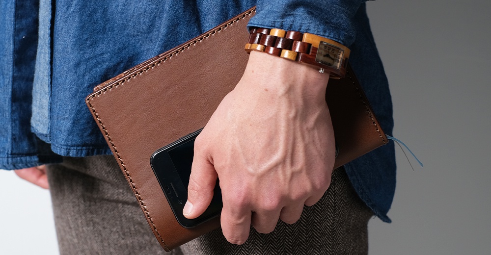 職人手作皮革B6記事本書套，經典棕色，車縫線明線設計，皮革質感佳，搭配黑色手機，展現簡約品味。