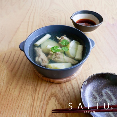 深灰色陶製圓鍋盛著雞湯，鍋內有雞肉塊、冬瓜塊及香菜，鍋旁有一小碟醬料，鍋下墊著木質鍋墊，上方放著一雙筷子。