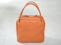 職人手作皮革Organ方形托特包，M尺寸，呈現自然紋理的橘棕色皮革，方正造型，頂部有提把及拉鍊開口，側邊有金屬鉚釘裝飾。