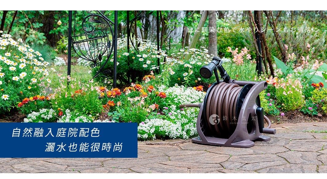 室外灑水組，包含一個深棕色捲盤，上面纏繞著相同顏色的水管，水管末端連接一個黑色噴頭。捲盤放置在鋪有石板的庭院中，背景是色彩繽紛的花圃與綠葉。