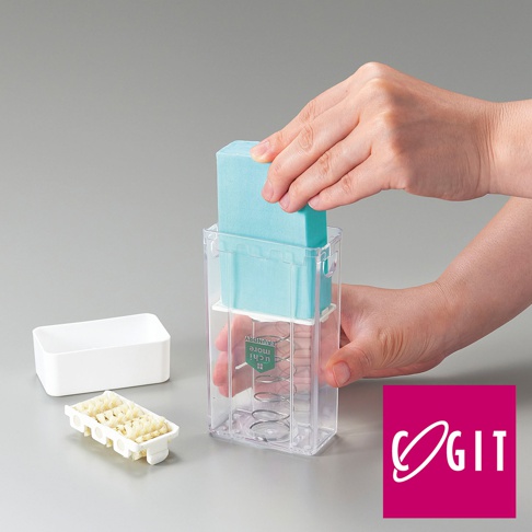 透明塑膠製的長方形洗衣皂盒，內含彈簧和藍綠色洗衣皂，旁邊擺放一個白色獨立盒和一個小型白色刷頭。