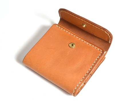 職人手作皮革方形短夾，顏色為淺棕色，材質為真皮。短夾設計有口袋及金屬按鈕，整體呈現簡潔實用的風格。