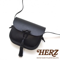 黑色皮革流蘇側背包，附有皮質繫帶與流蘇裝飾，風格簡約。