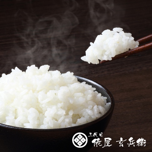 一碗冒著熱氣的飽滿白米飯，旁邊有一雙木筷夾起一小撮米飯。