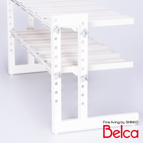 白色塑膠材質的伸縮槽下雙層L腳收納架，兩層層板皆為條狀設計，中間有可調節高度的固定栓，整體結構簡潔。