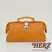 職人手作皮革長型迷你醫生包，採用自然色調皮革製作，配有金色圓形旋轉鎖扣及皮革提把，包身線條流暢，結構紮實，展現復古質感。