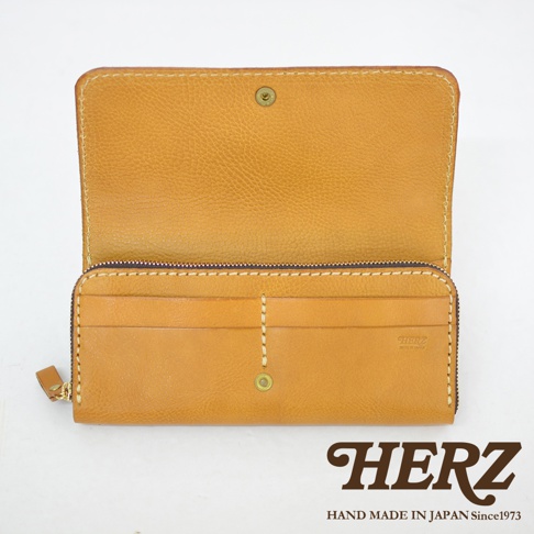 職人手作皮革長夾，呈現溫暖的焦糖色，寬口設計方便取用零錢。皮革表面帶有自然紋理，車縫線清晰。側邊有拉鍊，內部有多個卡槽。