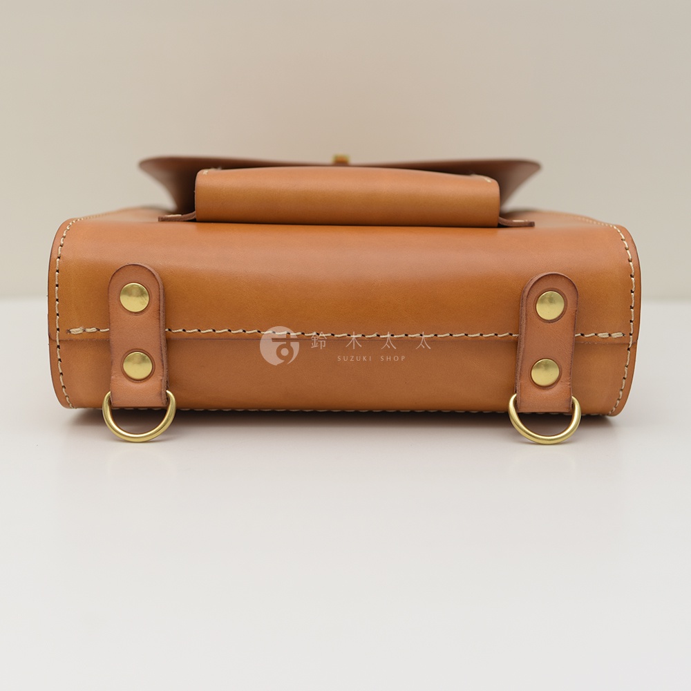 職人手作皮革復古後背包，以棕色皮革製成，設計簡約，側面有兩個金屬D型環。