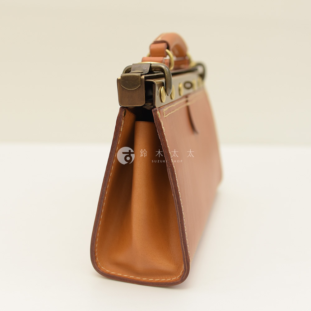 焦糖色皮革復古口金兩用手提包，側邊視角，可見金屬扣環和提把，縫線精緻。