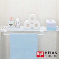 白色金屬製伸縮置物掛架，上方層架擺放著洗手乳、香氛瓶、三捲衛生紙及兩盒抽取式衛生紙，下方掛著一條淺藍色毛巾。