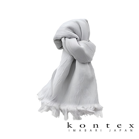 一件淺灰色、微透、輕柔的羊毛棉質混紡絲巾，頂部打結，垂墜感良好，底部有流蘇細節。