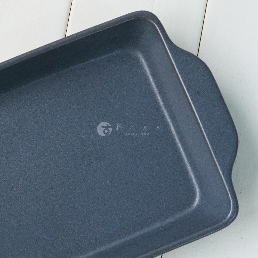 深灰色耐熱陶製烤盤，長方形平底設計，兩側有提把，表面呈現細微顆粒質感。