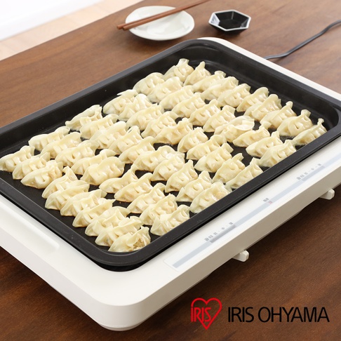 左右溫控電烤盤 WHP-012，黑色烤盤上擺放著整齊排列的淺黃色煎餃，烤盤下方是白色主機，側面有控制面板。