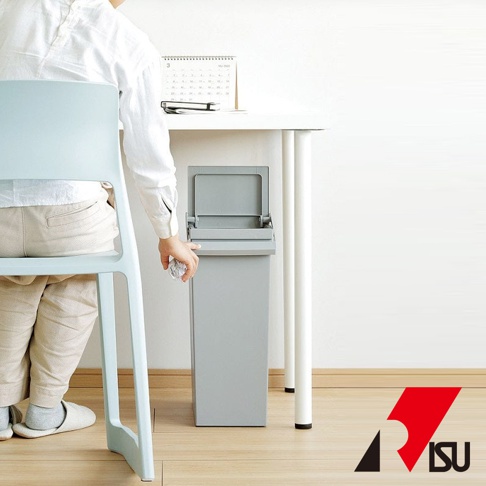 灰色簡約設計風格按壓雙開型分類垃圾桶，搭配淺藍色椅子和白色桌面，展示其置於桌邊的擺放情境。