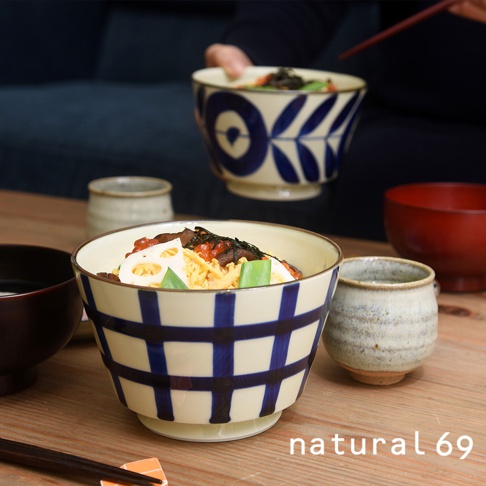 一個裝有日式料理的陶瓷丼碗，碗身以米白色為底，飾有藍色網格紋路，碗內盛有鮭魚卵、香菇、炒蛋、蓮藕片及海苔絲等配料。