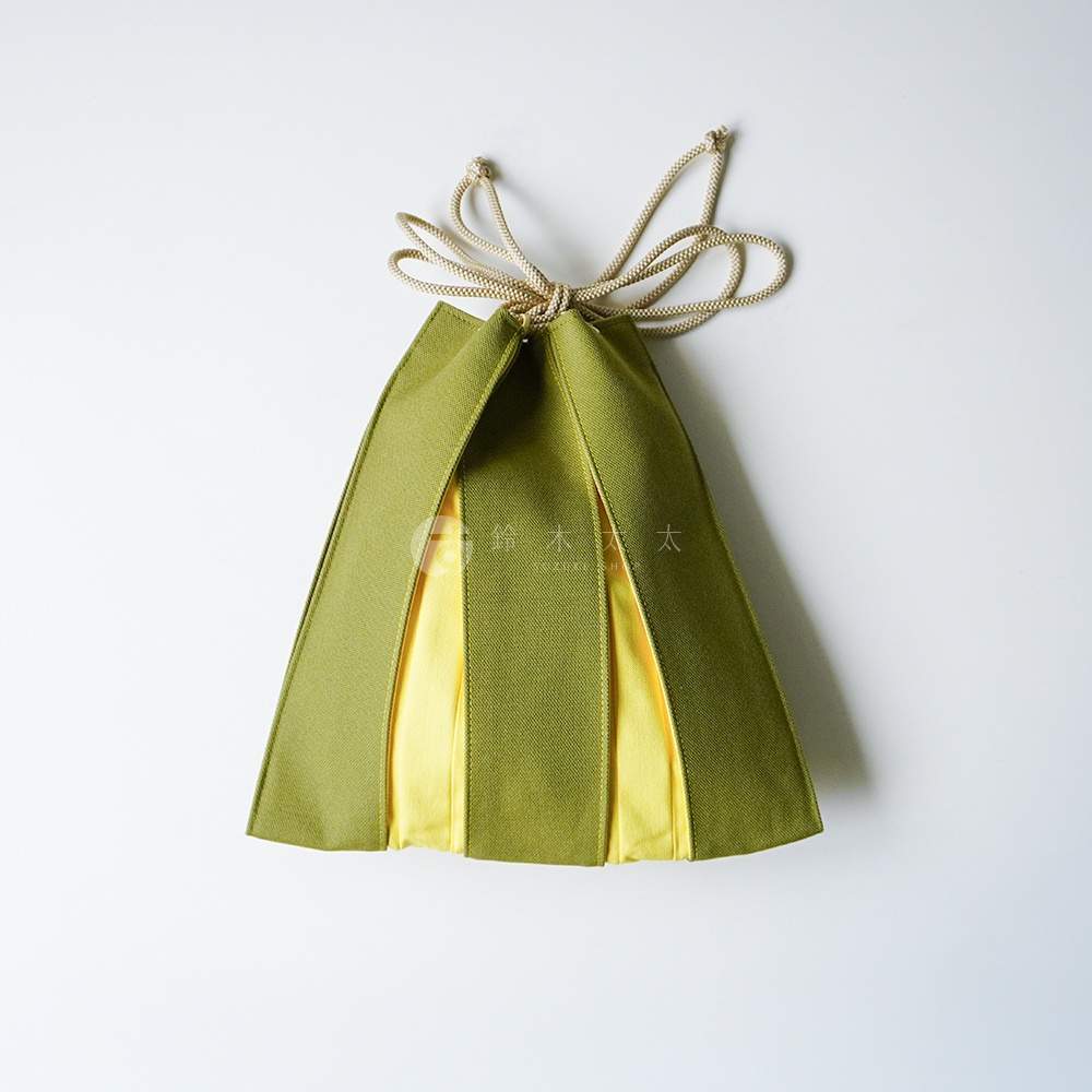 這是一款造型獨特的京都KOSHO ougi帆布信玄袋，外層採用橄欖綠色帆布，內襯為對比鮮明的亮黃色布料，外觀呈現如扇形般的拼接結構，袋口搭配米白色束口繩，整體呈現簡潔現代的日式美學。