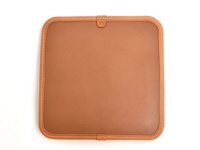 職人手作皮革方形坐墊，採用棕褐色皮革，四邊以白色縫線包邊，角落圓潤，頂部中央有一個皮革標籤。