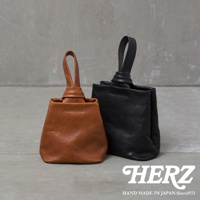 職人手作皮革Organ單柄手提包，一款為棕色，一款為黑色。兩款均為簡約的單柄設計，皮革材質，包身呈現自然垂墜感，手柄處以打結設計為特色。