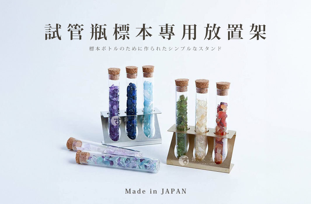 展示架上擺放著多個玻璃試管瓶，瓶內裝有不同顏色的小顆粒寶石，如紫色、藍色、綠色、黃色和紅色。試管瓶配有軟木塞。展示架為金屬材質，呈現簡約設計。