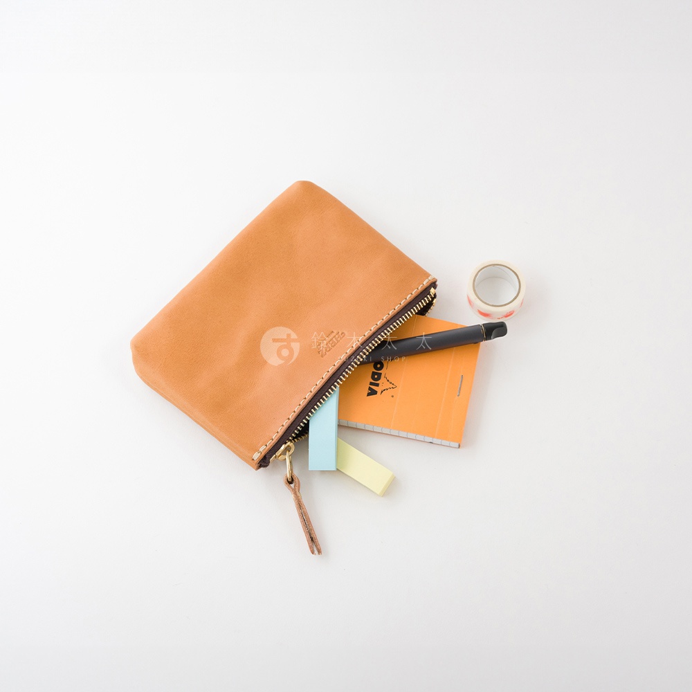 職人手作皮革長方形拉鍊收納包，淺棕色皮革材質，拉鍊開合，包內有筆、小筆記本及便利貼，側邊有裝飾拉繩。