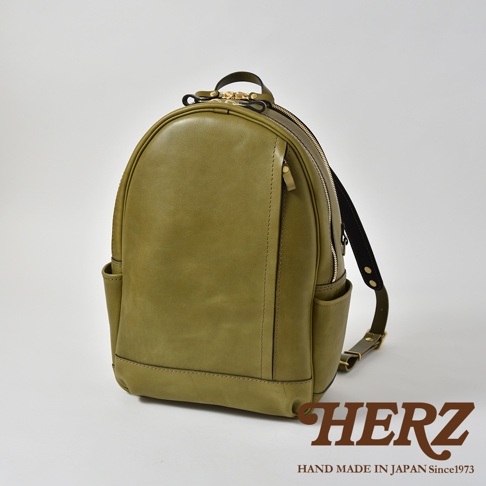 橄欖綠皮革多功能後背包 R-21，以職人手作工藝製作，設有雙向拉鍊主袋、前方拉鍊口袋、兩側開放式側袋及可調節肩帶。