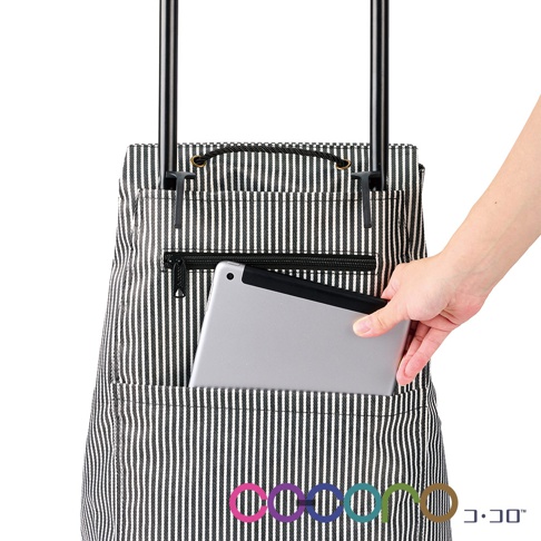 黑色與白色細直條紋帆布材質購物車，配有拉鍊前袋，其中可見一個銀色平板電腦，另一手正將其放入。