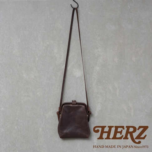 職人手作皮革Organ迷你杜勒斯側背包，深棕色，光滑皮革，設有可調節長度的細長肩帶，包身呈口金設計，配有金屬扣環，整體呈現簡約復古風格。