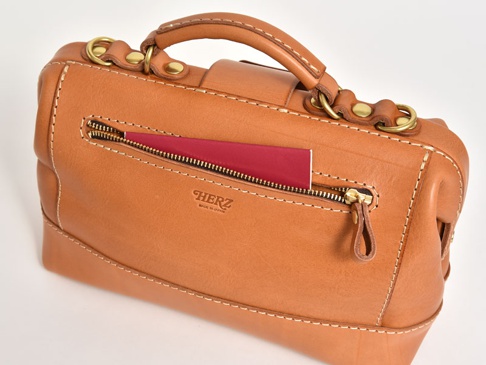 職人手作皮革兩用迷你口金單肩包，採用鞣製皮革製成，呈現自然的棕褐色。包款設有外部拉鍊口袋，可放入護照，並配有手提把和金屬扣環。