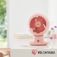 粉色圓形空氣循環扇，扇葉為珊瑚紅，帶有 IRIS OHYAMA 標誌。風扇置於白色桌面，旁邊有簡約遙控器。
