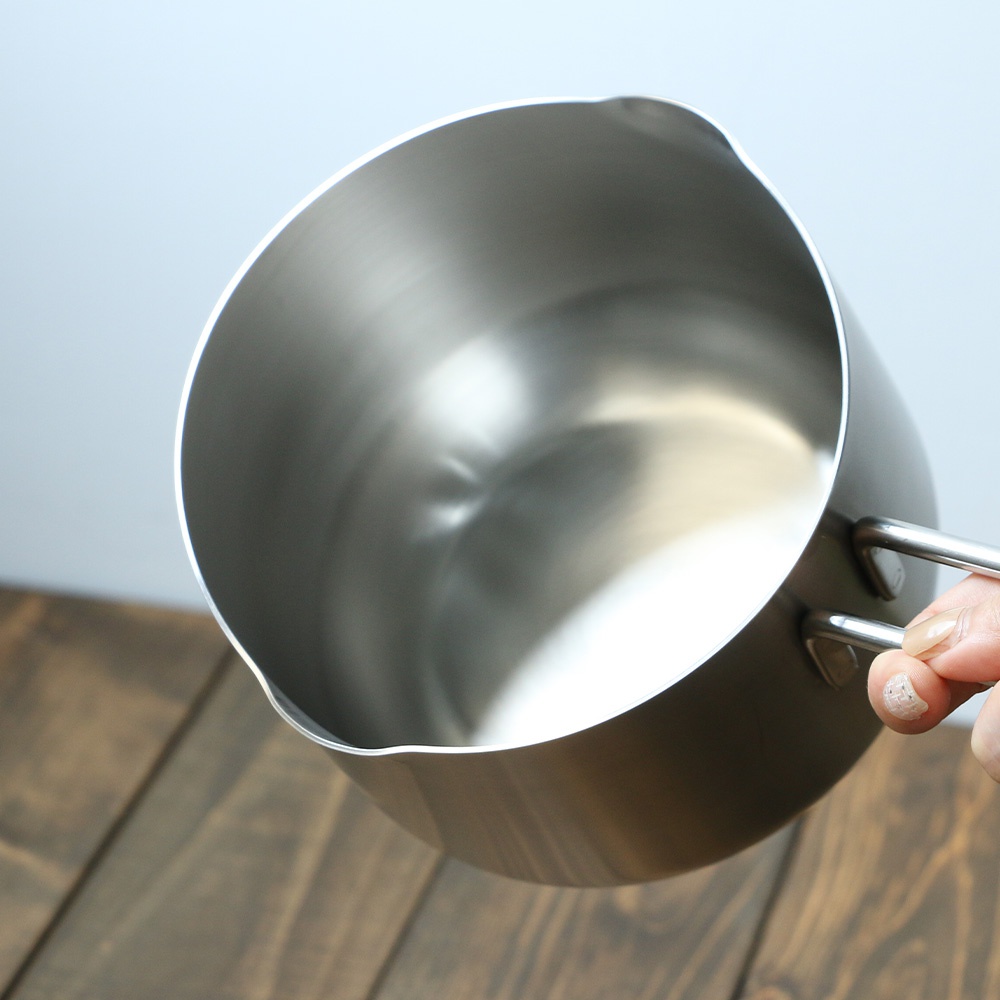 不鏽鋼雙口牛奶鍋，鍋身為銀色，材質為不鏽鋼，一側有兩個把手，鍋緣有雙邊傾倒口設計。