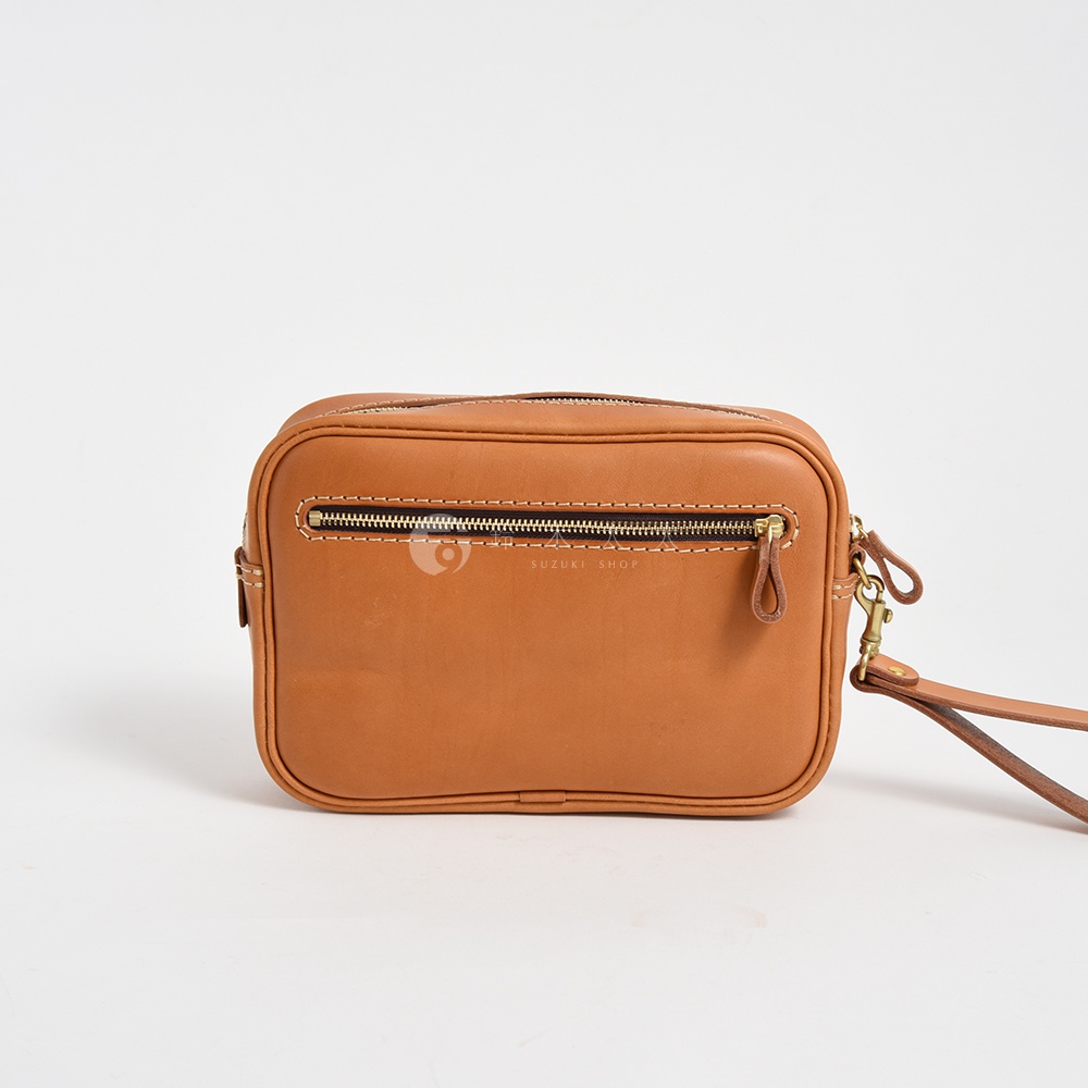 棕色皮革手提包，正面有拉鍊開口，側邊有可拆卸的皮革掛繩扣環，由堅固的縫線製成。