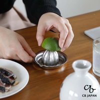 CB JAPAN 日本製不鏽鋼檸檬榨汁器，使用者正用手將半顆檸檬壓入榨汁器中。