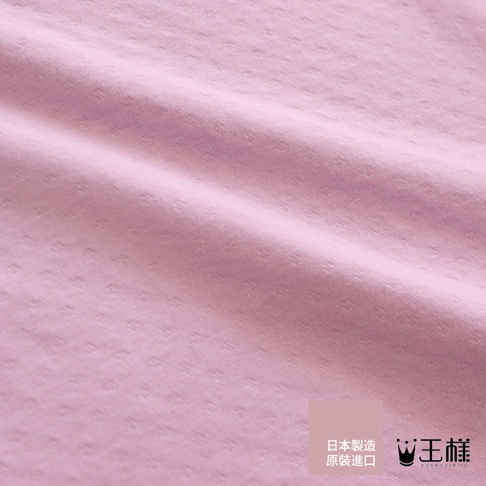 粉色織物材質，表面有細小的點狀紋理，呈現細緻的織紋感，布料有自然的褶皺。