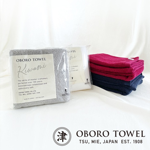 一疊粉紅色和深藍色細纖維浴巾，旁邊是兩包分別為淺灰色和白色的細纖維浴巾，皆標有「OBORO TOWEL」字樣。