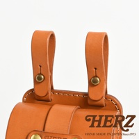 職人手作皮革經典腰袋，展示了兩條棕色皮革掛帶，由黃銅铆釘固定，腰袋主體為相同材質和顏色的皮革，帶有品牌標誌。