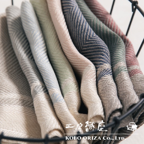 一堆純亞麻斜紋織法的廚房拭巾，呈現米白、淺藍、淡綠、粉紅、深藍、墨綠、磚紅等多種柔和色彩，材質觸感細緻。