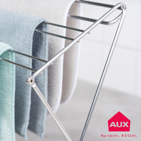 金屬材質的折疊式小物晾曬架，掛有淺藍色、灰色和米白色毛巾，設計簡潔實用。