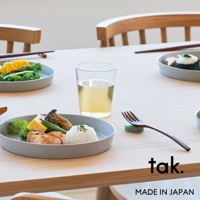 一套四個灰色、透明、防摔的塑膠水杯，置於木桌上，旁邊有裝有食物的盤子和餐具。