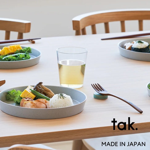 一套四個灰色、透明、防摔的塑膠水杯，置於木桌上，旁邊有裝有食物的盤子和餐具。