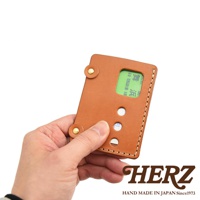 日本HERZ職人手作皮革交通卡收納夾，棕色皮革材質，裝有綠色卡片，展示了品牌Logo及「HAND MADE IN JAPAN Since1973」字樣。