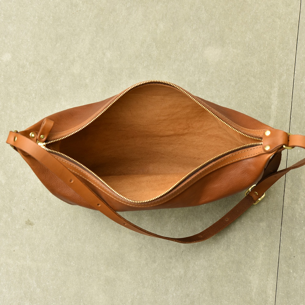 職人手作皮革Organ單肩半月包，採用咖啡色皮革，設有金色拉鍊及可調節式皮質肩帶，風格簡約。