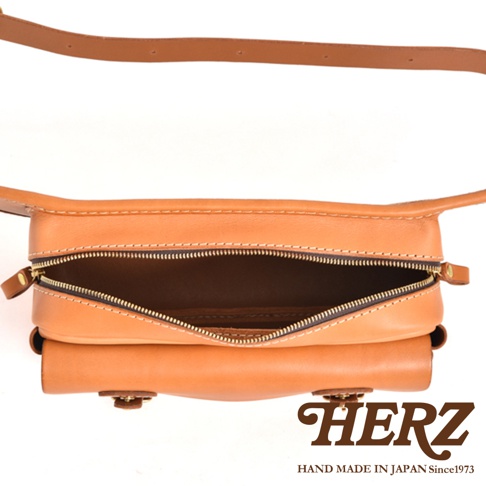 職人手作皮革騎士隨身斜背包，淺棕色皮革材質，設有拉鍊開口，可見內部空間，配有同色系皮革背帶。