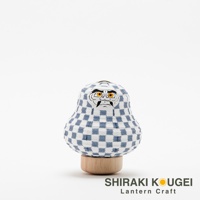 達摩不倒翁迷你提燈，白色紙質燈籠身印有藍色棋盤格紋，臉部描繪黑色眉毛、鬍鬚及橙色眼睛。提燈置於圓形木質底座上。