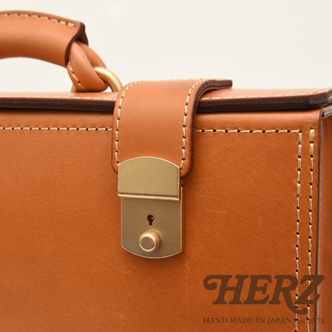 職人手作皮革兩用機師箱，以 tan 色皮革製成，搭配金色鎖扣和縫線細節，展現經典復古風格。