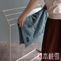 一條藍綠色、帶有菱形紋路的高密度吸水浴墊，標籤上有「sensui」字樣，被一隻手放在白色晾衣架上。