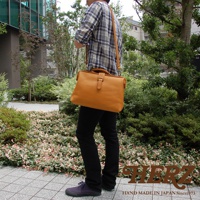 職人手作皮革軟式杜勒斯包，黃褐色皮革材質，附有金屬扣環的翻蓋設計，可斜背或肩背。