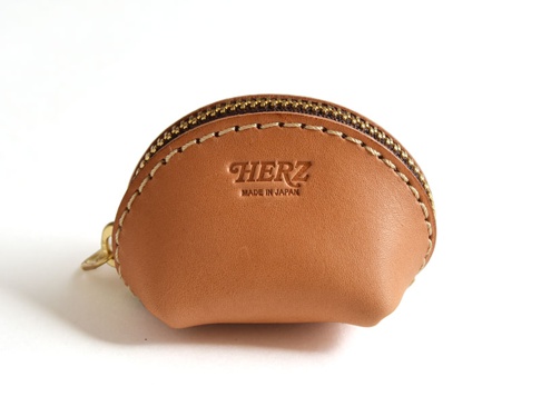 咖啡色皮革貝殼造型零錢包，頂部有黃銅拉鍊，側面縫線細緻，正面壓印有「HERZ」和「MADE IN JAPAN」字樣。