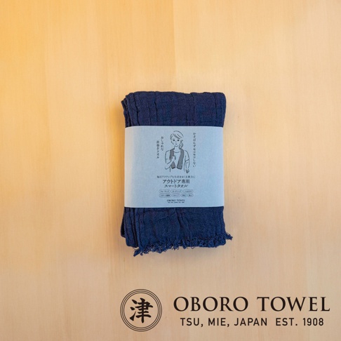 深藍色三層紗純棉掛脖毛巾，帶有簡約包裝紙，上面印有女性圖案和日文說明。